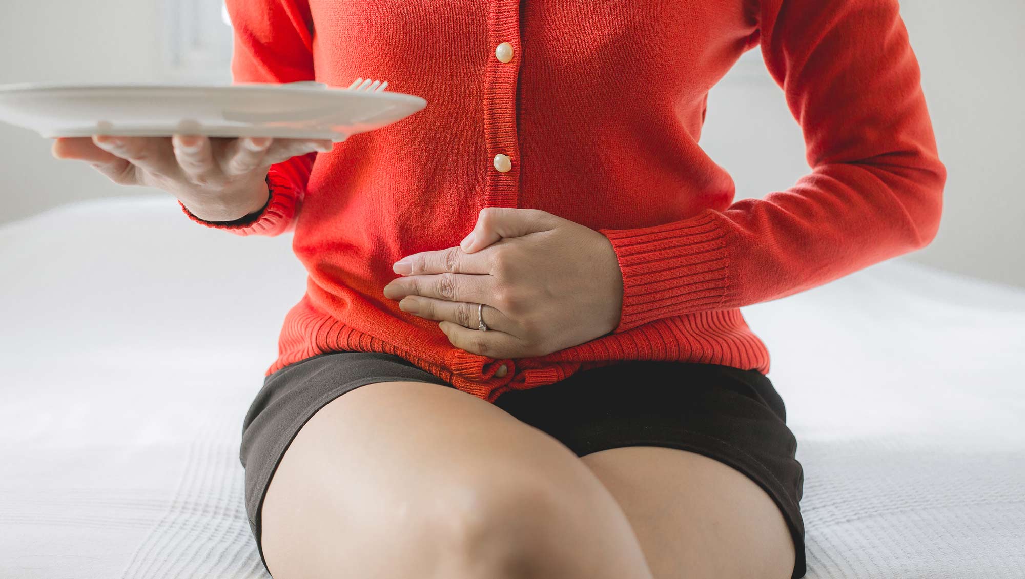 a woman holds an empty plate with her hand on her stomach