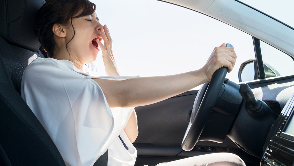 a woman yawns while driving