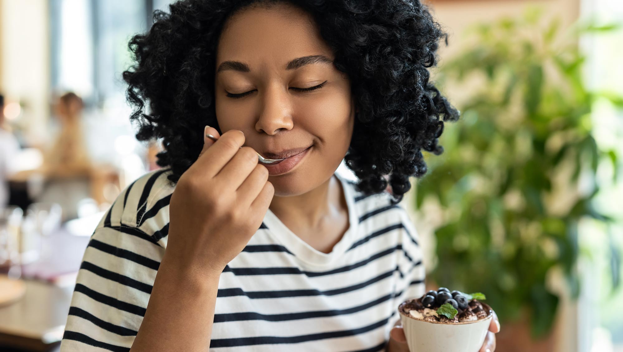 a woman enjoys a bite of her tiramisu
