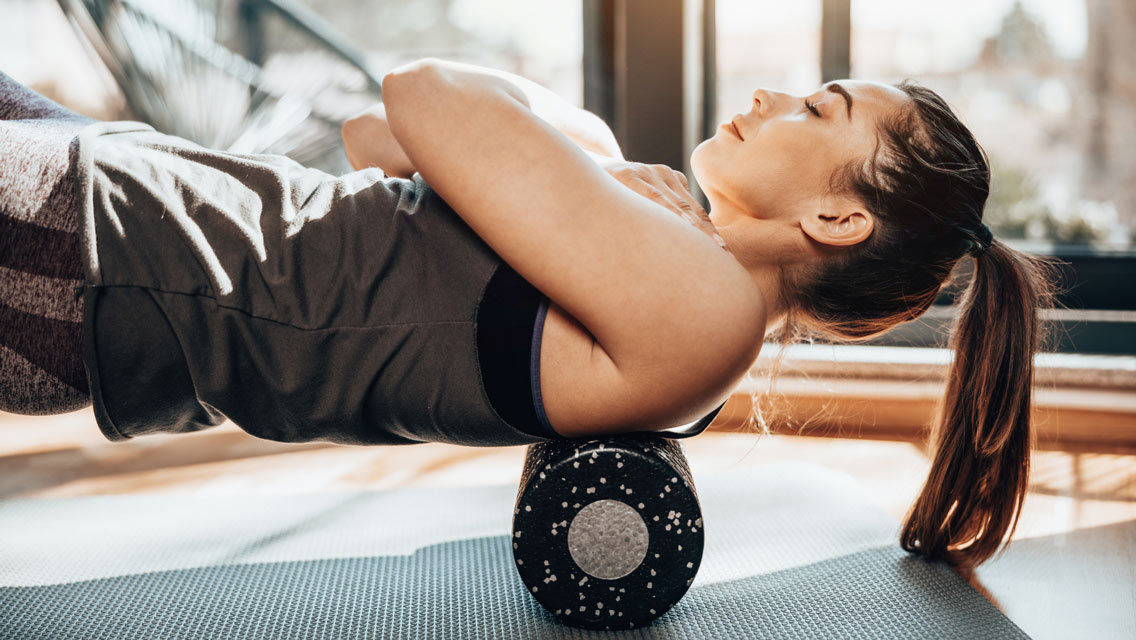 a woman foam rolling her upper back