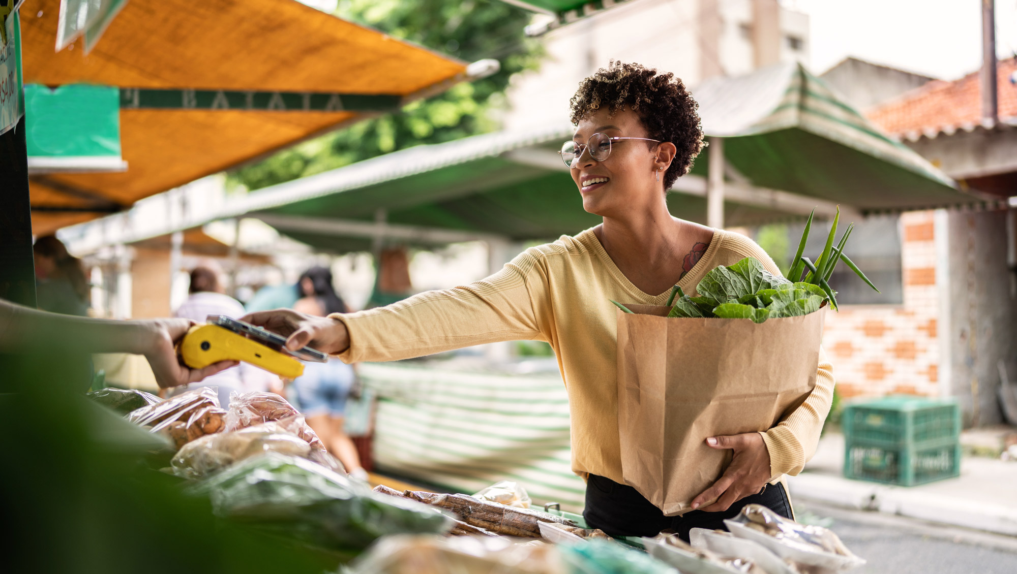 a woman purchases a bag of produce from a street vendor