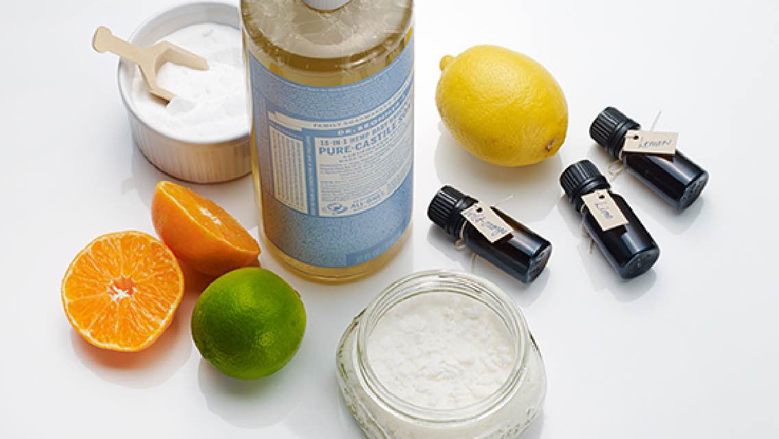 Various supplies used to make cleaning solutions, including soap, citrus, and essential oils.
