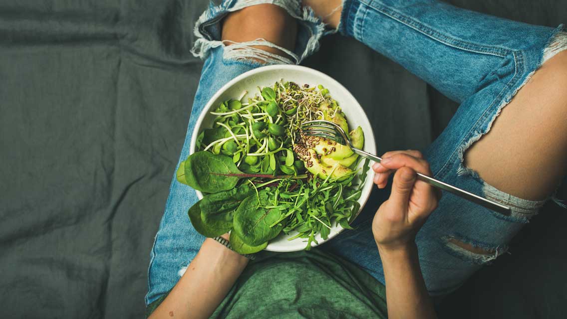 a person eats a healthy bowl filled with green produce