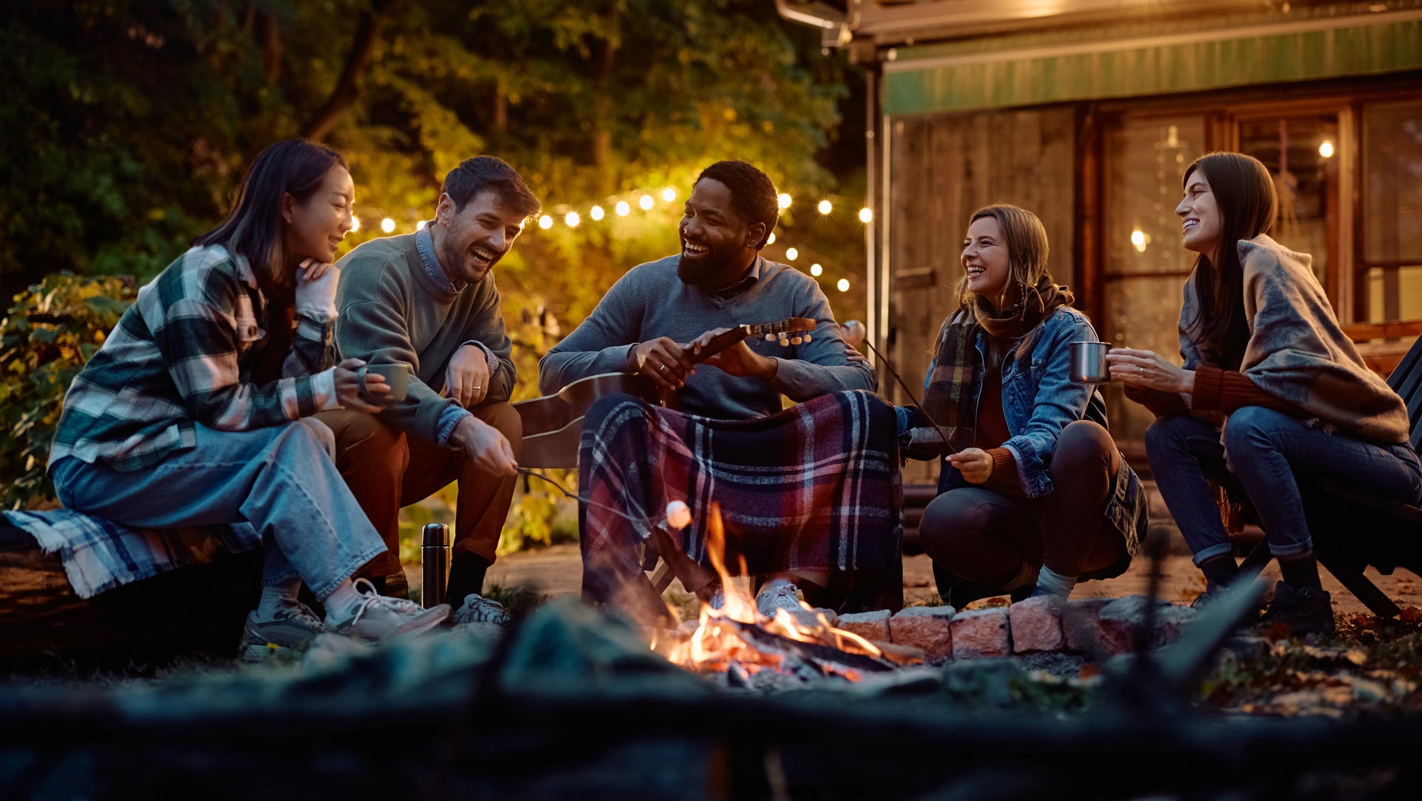 friends chat and roast s'mores around a campfire