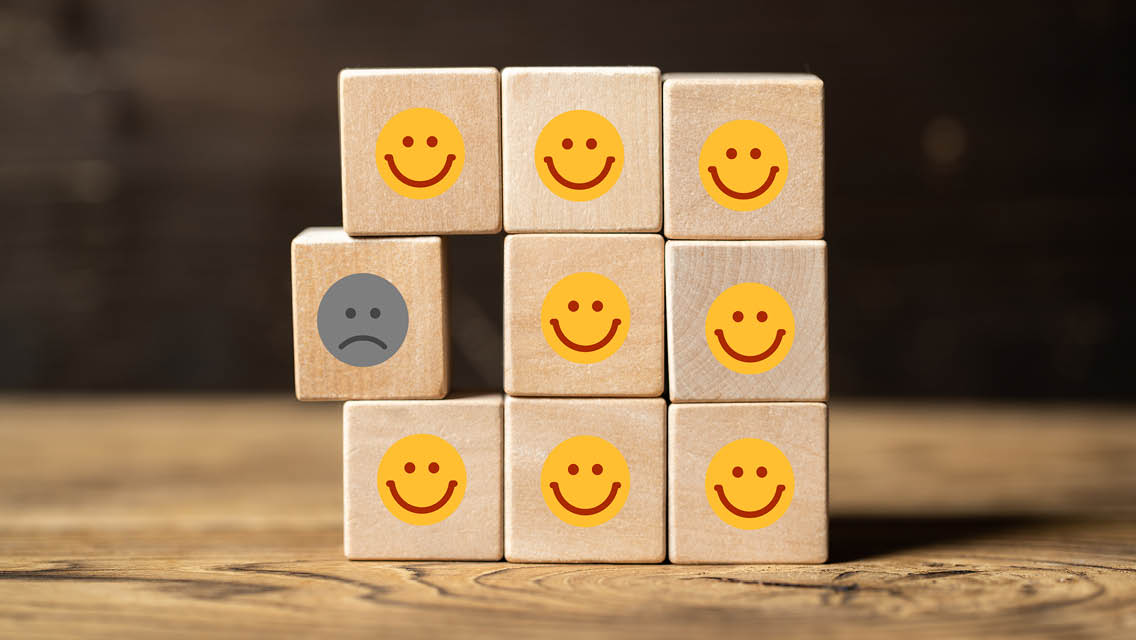 a set of blocks with smiling faces and one that is frowning