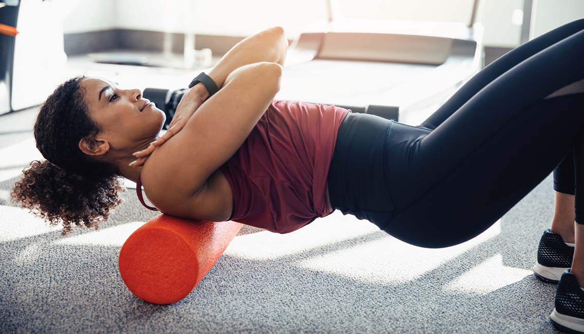 a woman foam rolling her upper back