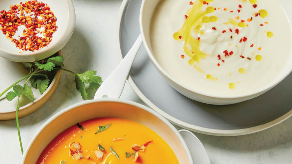 Two bowls of creamy vegetable soup.