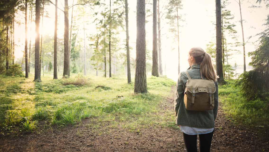 a woman walking on a wooded trail