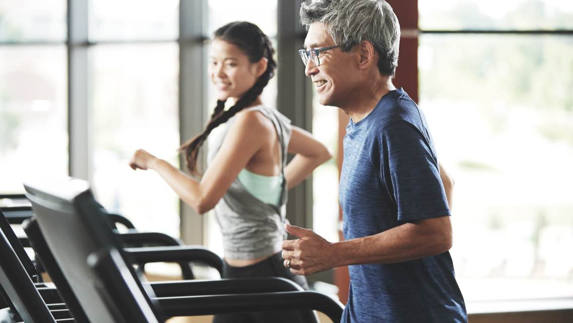 Two people run on a treadmill.