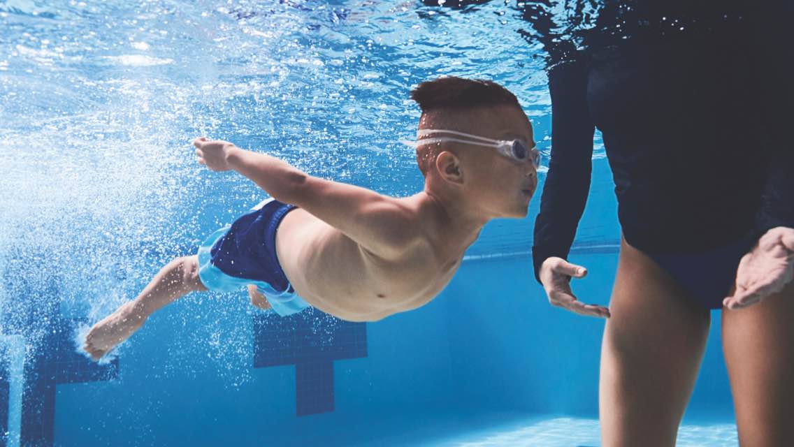 A child swims underwater in a pool.