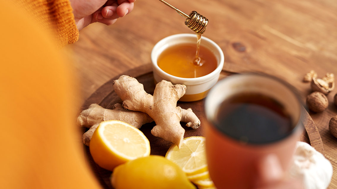 Person making ginger tea with honey and lemon