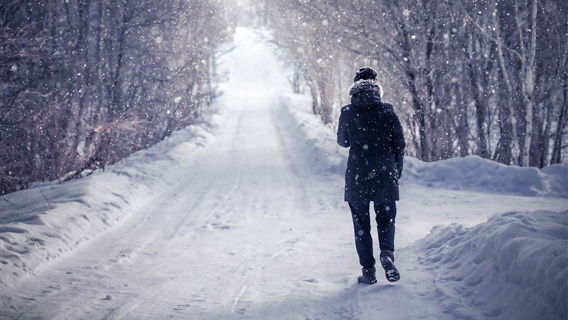 a person walks down a snowy, desolate road