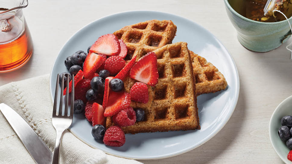 Plate of waffles with fruit on top.