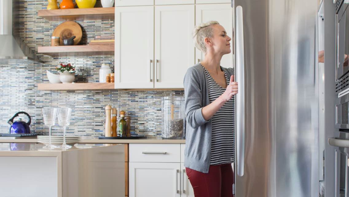 Woman reaching into her refrigerator