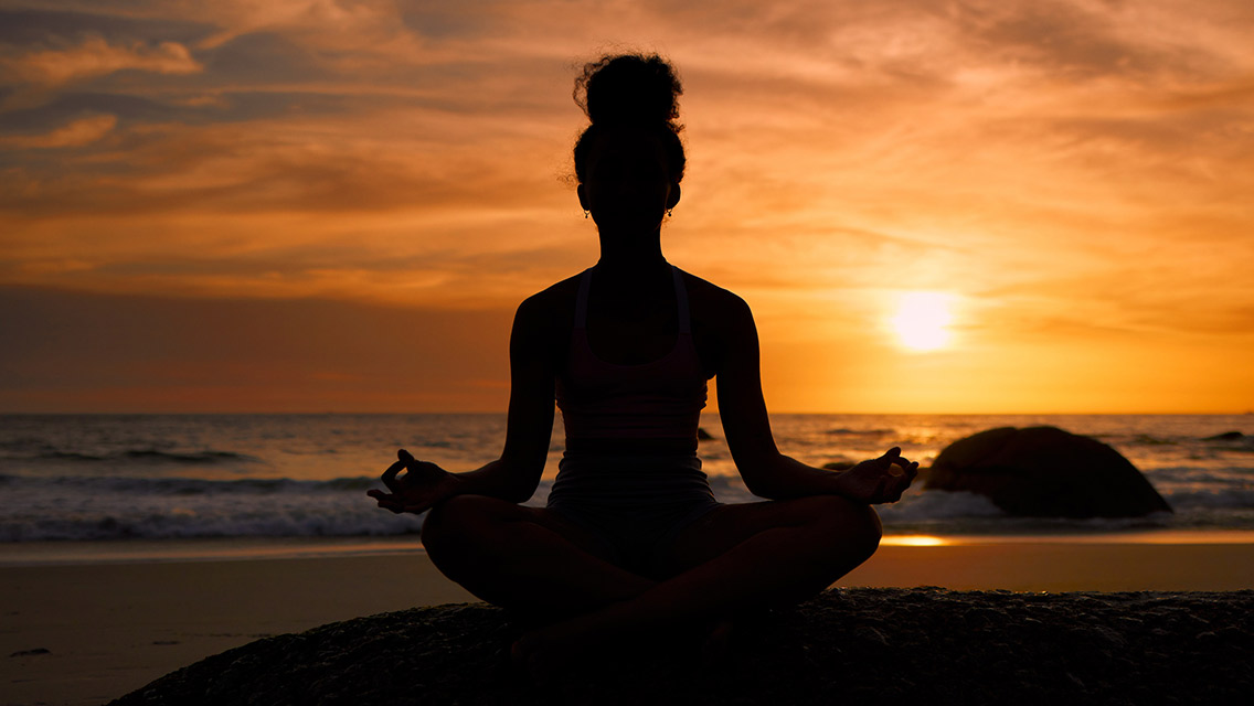 Woman doing yoga during sunset