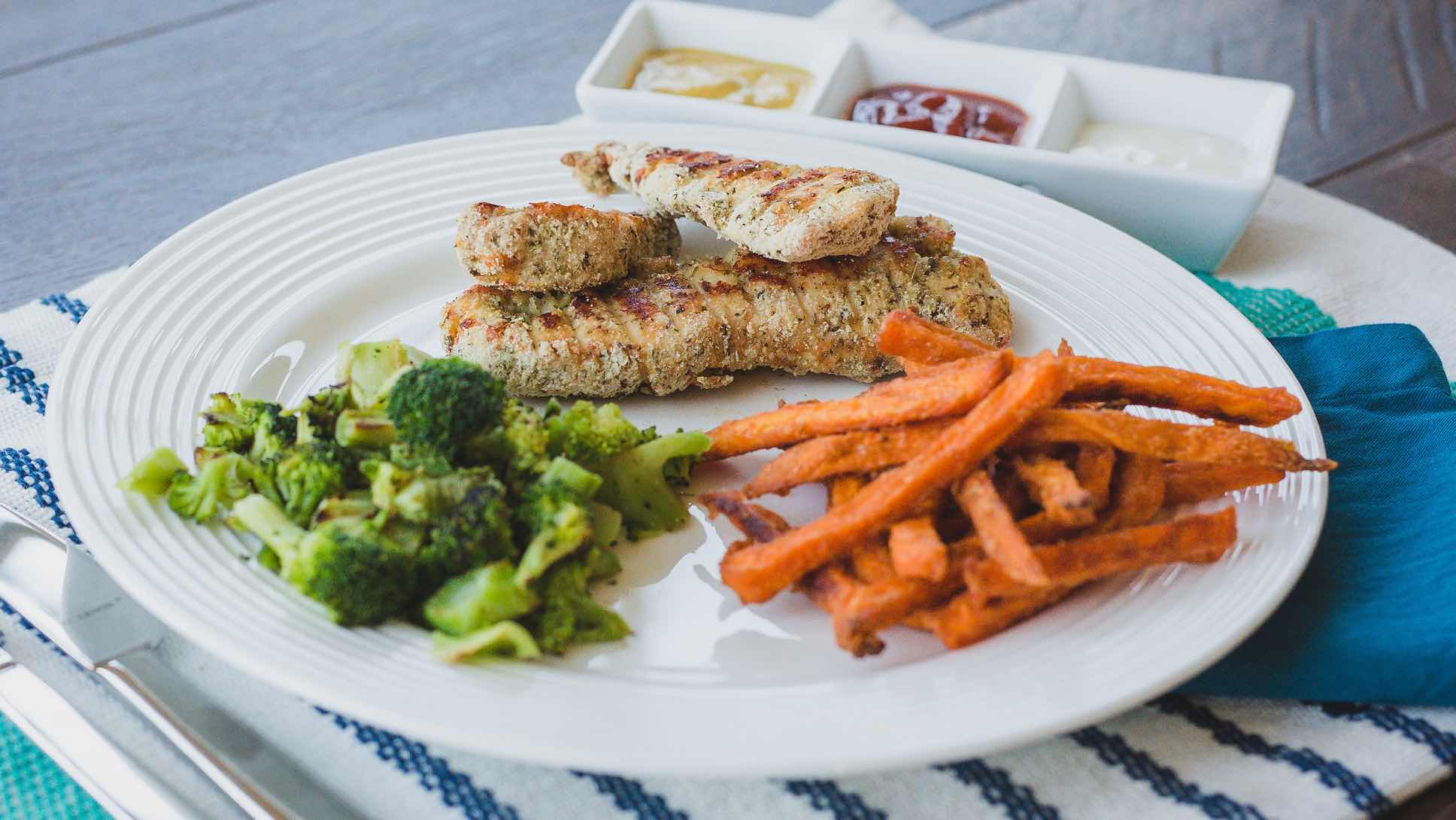 Chicken tenders, broccoli and sweet potato fries on a platet