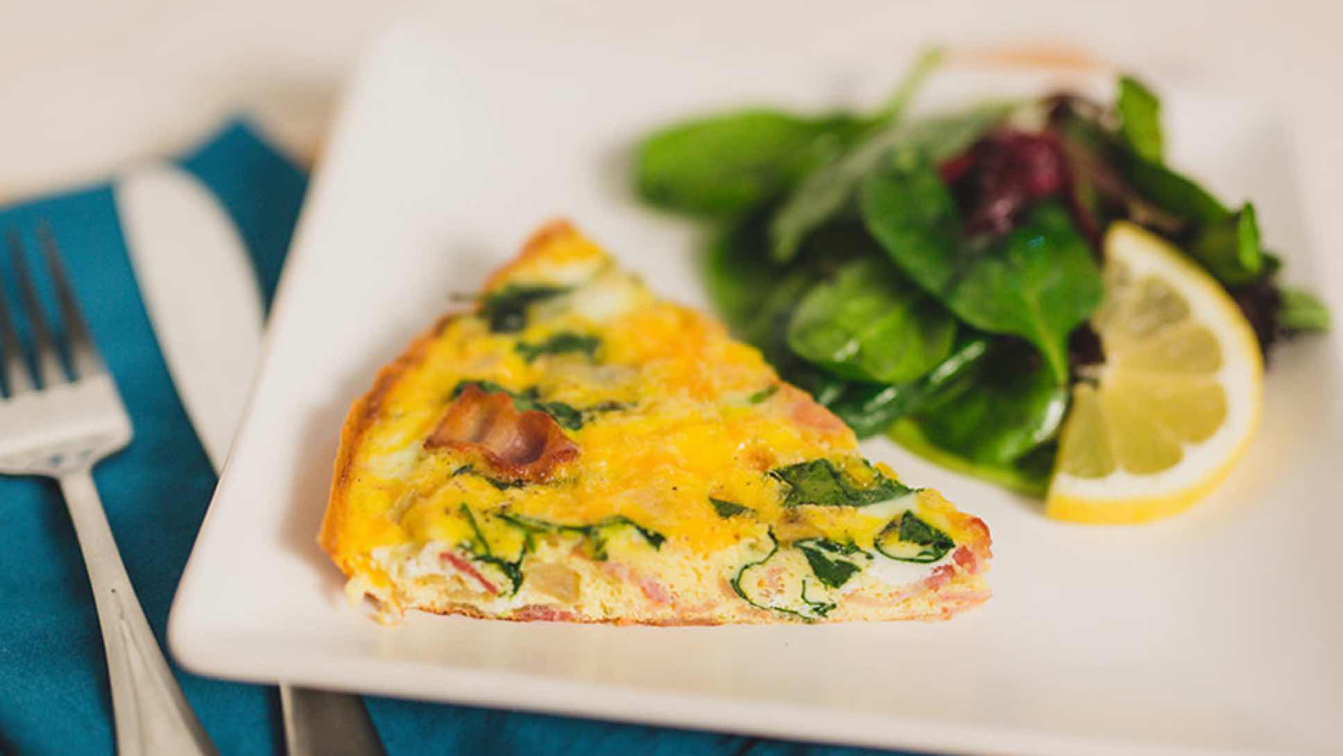 Egg frittata on a plate with mixed greens.