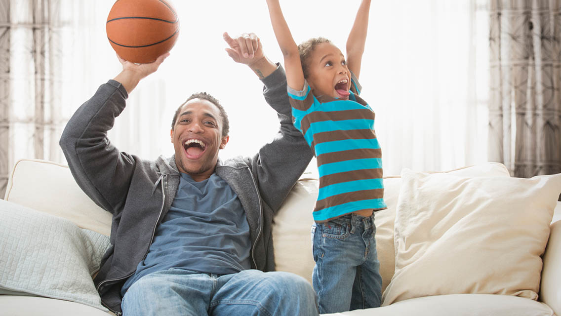 Father and son playing with a basketball at home.