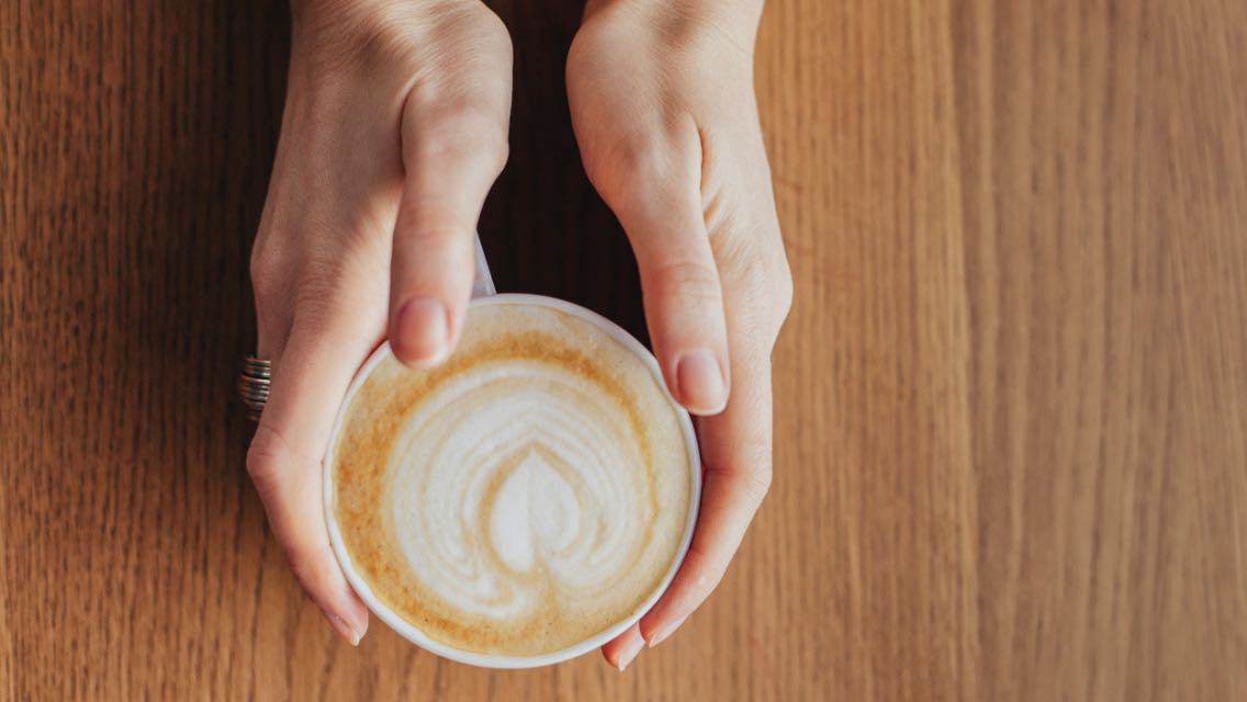 A woman's hands holding a cup of coffee.