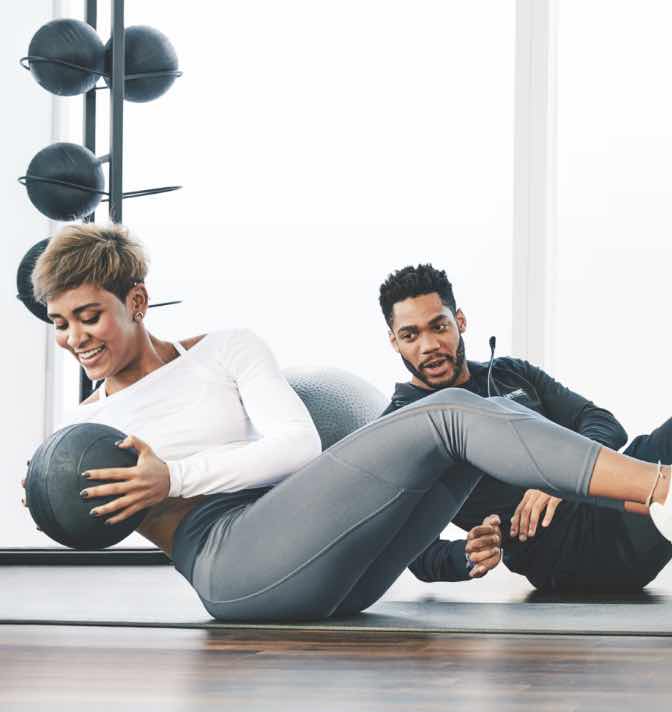 A trainer instructing a client using a medicine ball.