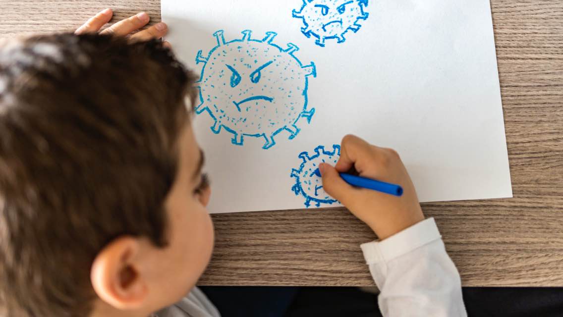 A child draws angry faces on a piece of paper.