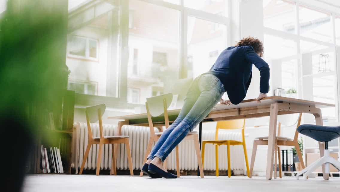 Woman doing a pushup on a desk.