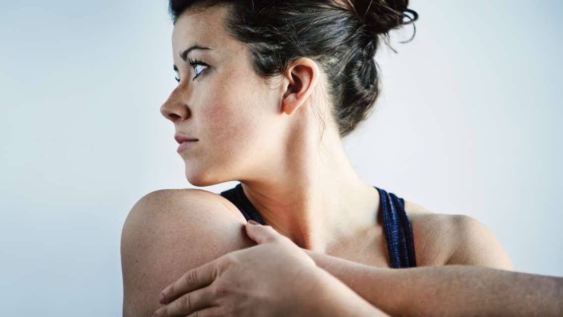 A woman stretching her arms, looking off to the side.