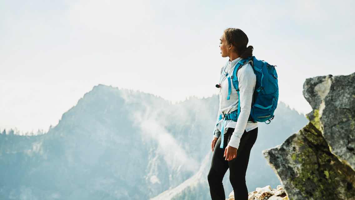 A woman on a hike looking at a mountain landscape.