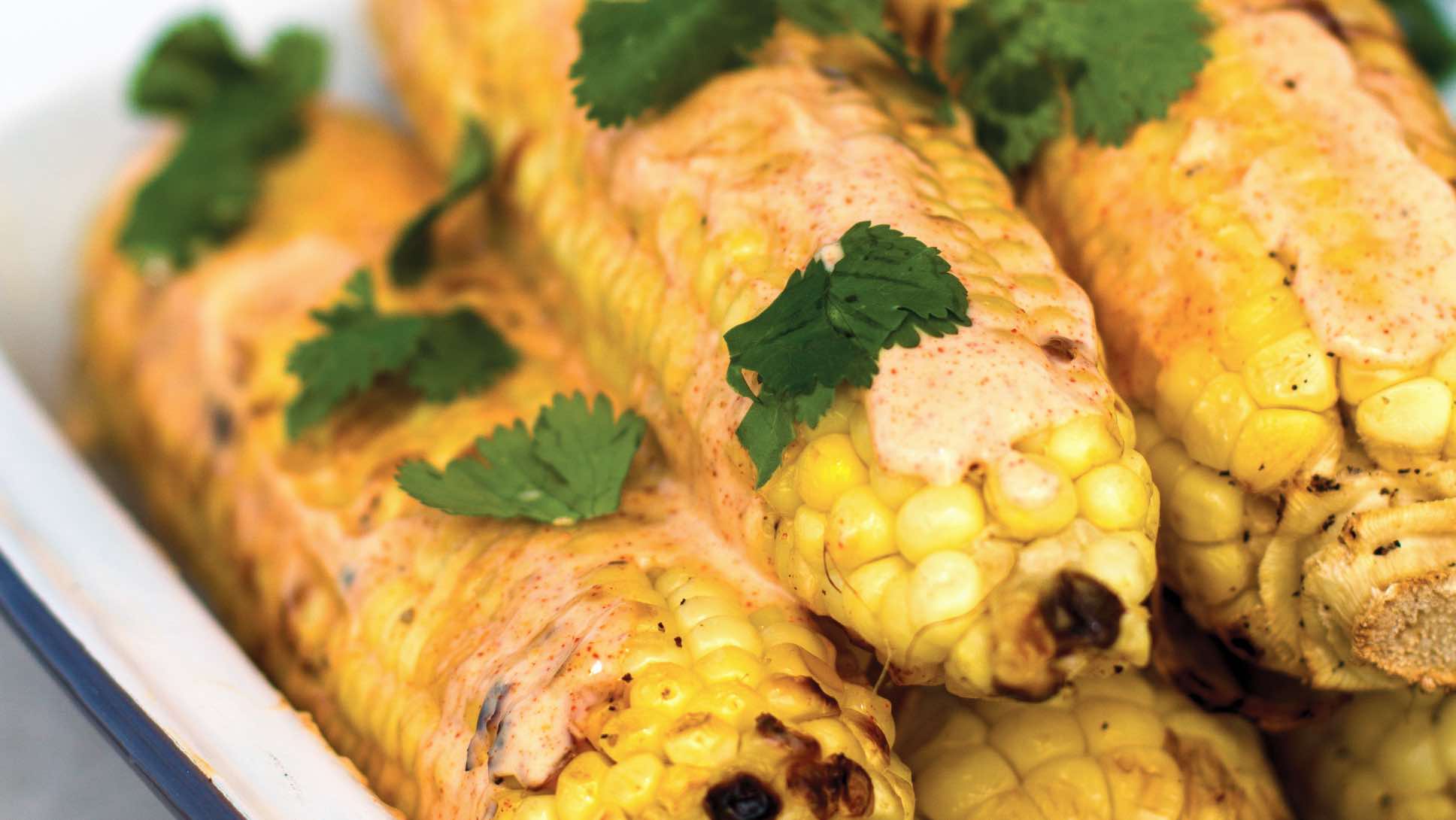 Cobs of grilled corn with ancho-lime mayo and cilantro.