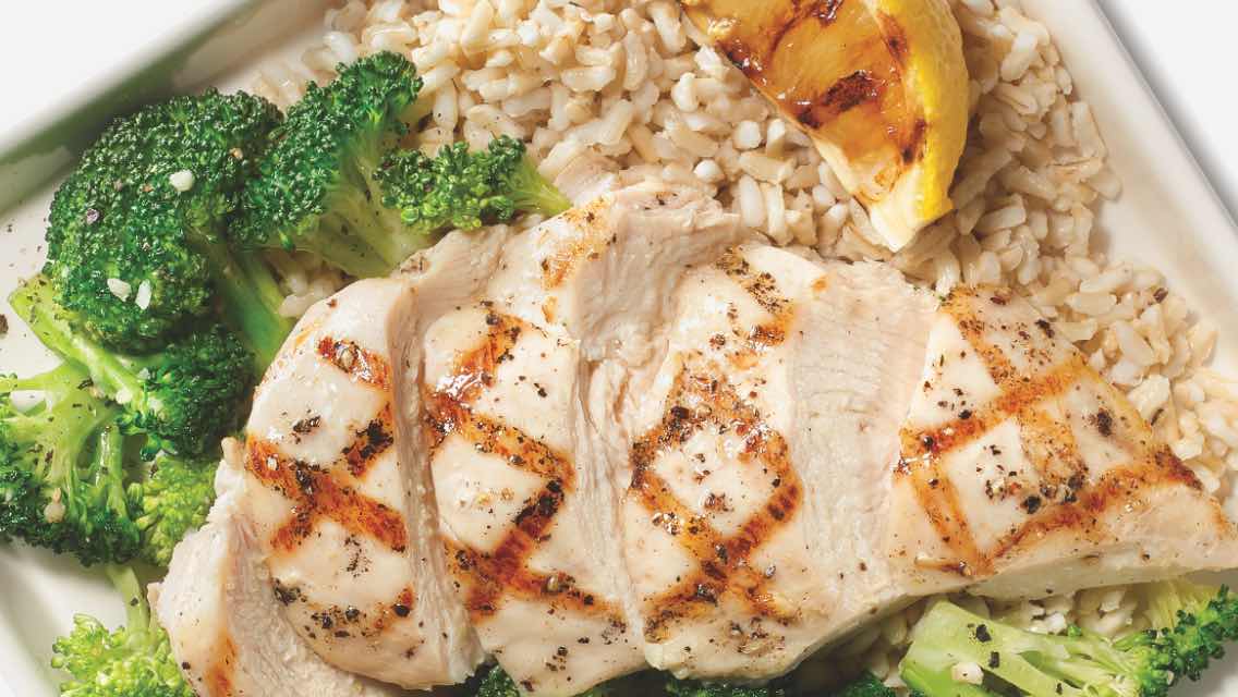 A close up of grilled chicken with broccoli florets.