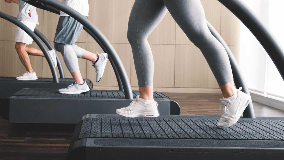 A close up of three people's legs and feet who are running on three different treadmills.