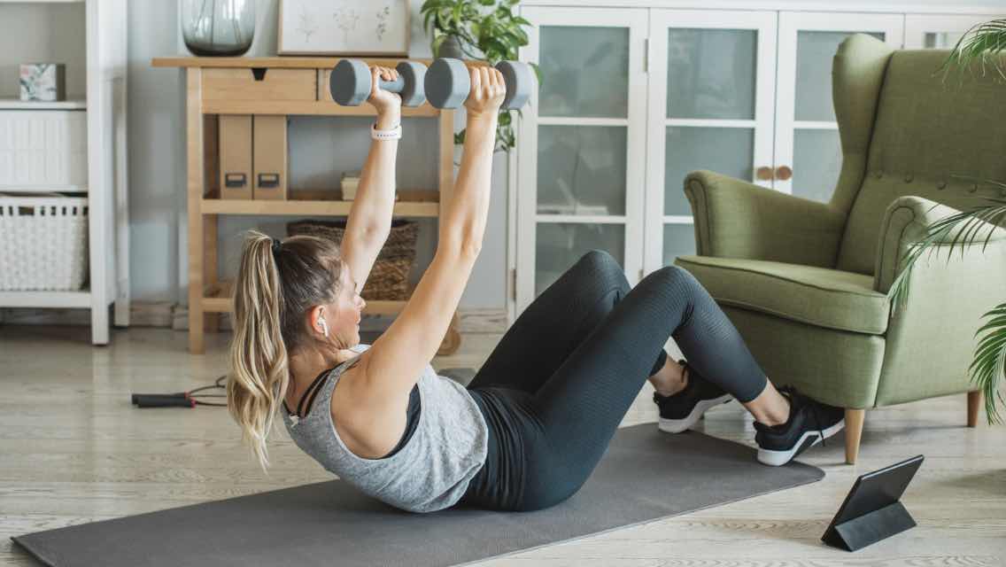 a woman doing a sit up with weights at home