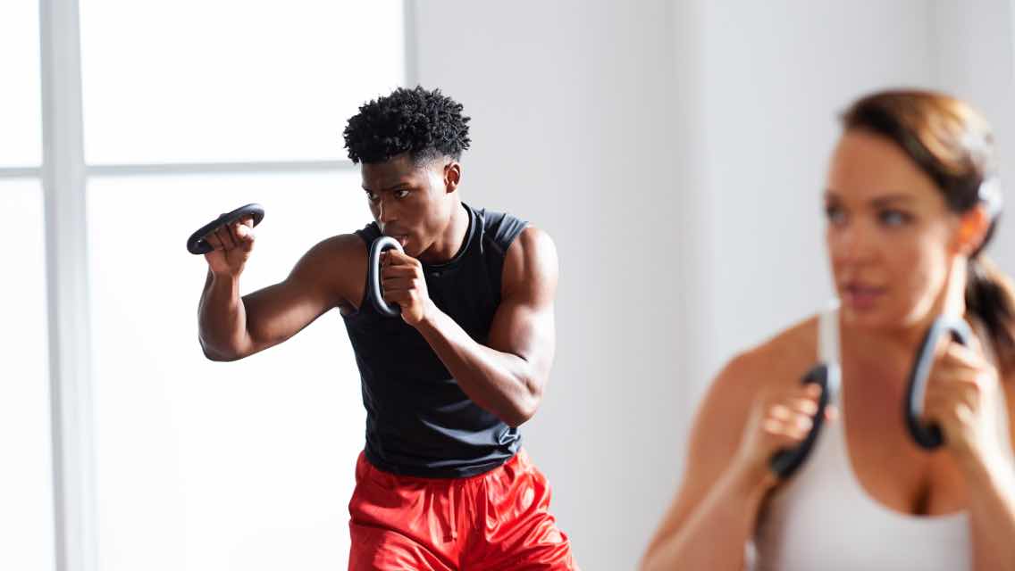A man and a woman in a boxing class at a fitness facility.