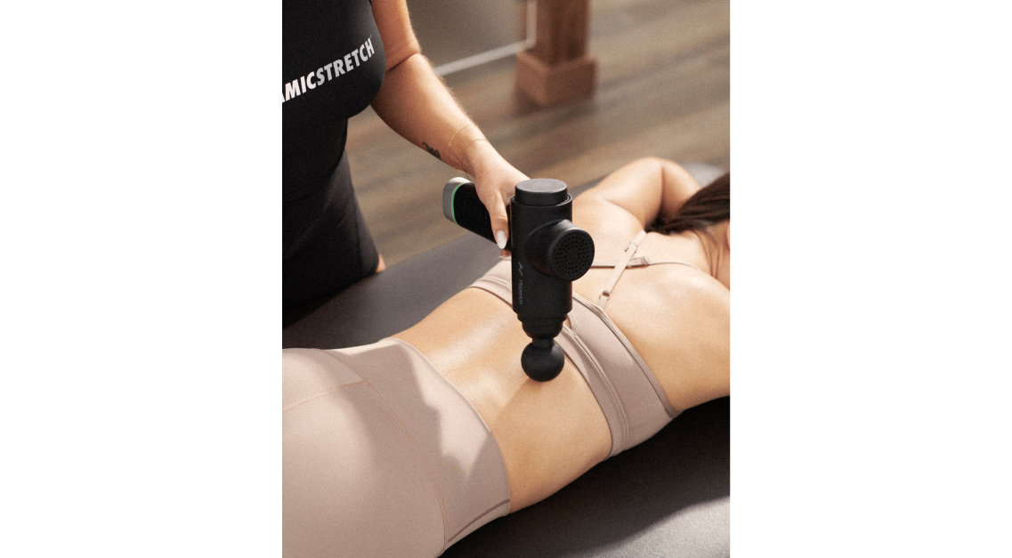A Dynamic Stretch Specialist using a percussive device on a client.