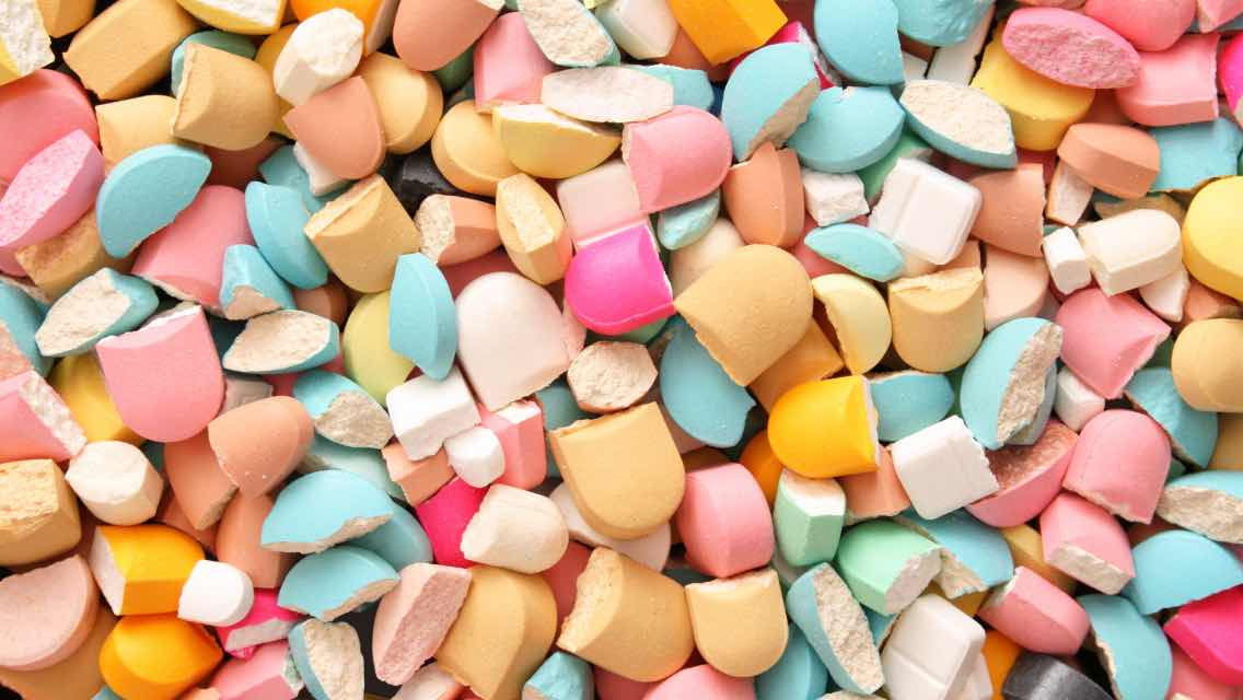 A bunch of different colored broken pills.
