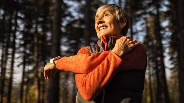 a woman stretches while hiking in a woods