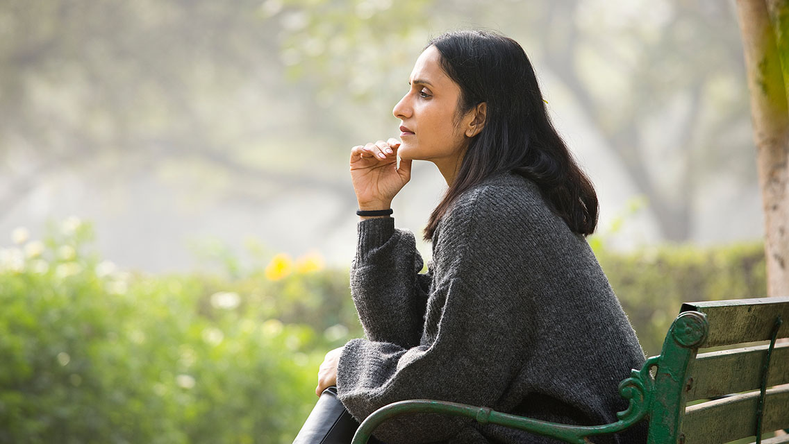 a woman ruminates while sitting in a park