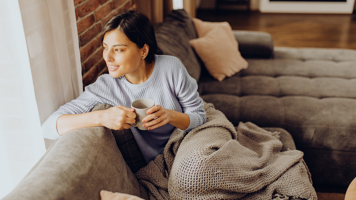 Woman enjoying coffee on cozy sofa