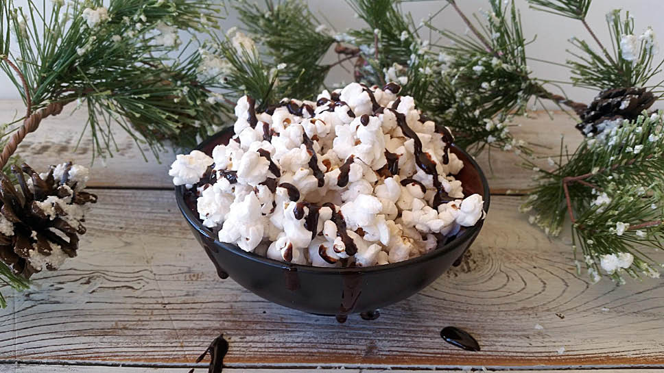 a bowl of popcorn drizzled with chocolate sauce