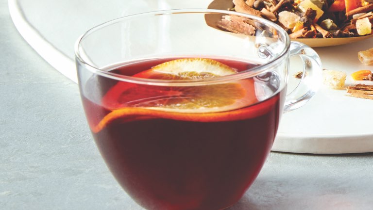 a glass mug of mulled hibiscus cider with a slice of lemon
