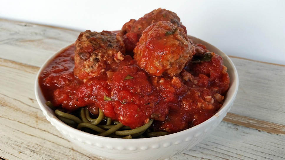 a bowl of whole wheat pasta topped with meatballs and pasta sauce