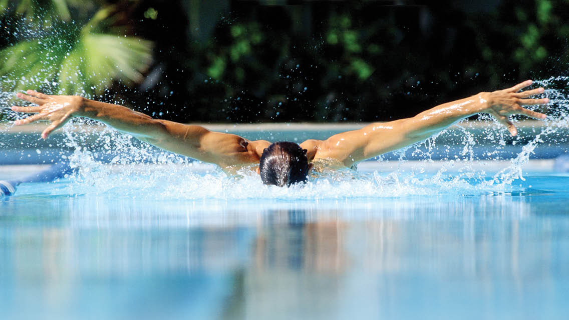 a man performs the butterfly stroke in a pool
