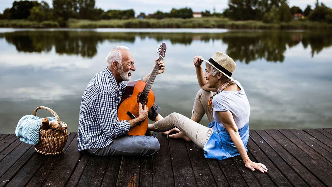 Older couple playing music by a lake.