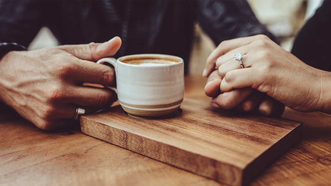 Close-up of loving couple holding hands at coffee shop.