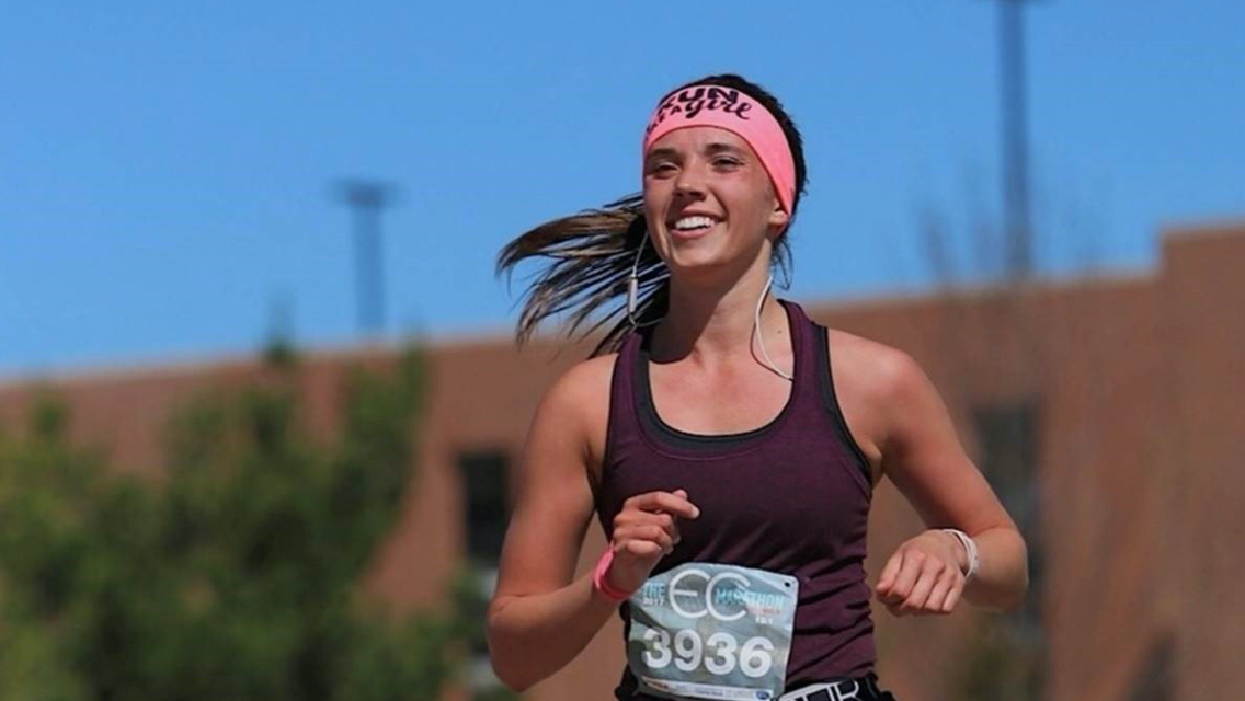 A young female Life Time member running a race outside.
