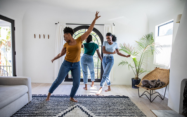 Three adult women dancing in living room