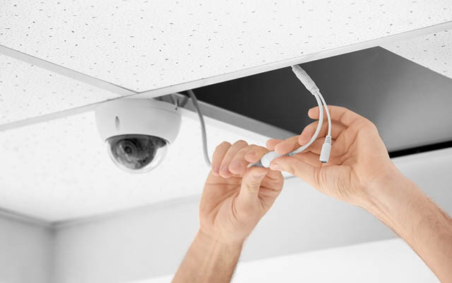 Disembodied hands installing a hidden camera in the ceiling
