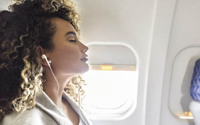Person sitting on a plane with earbuds