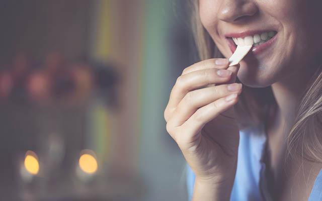 woman putting stick of gum in mouth