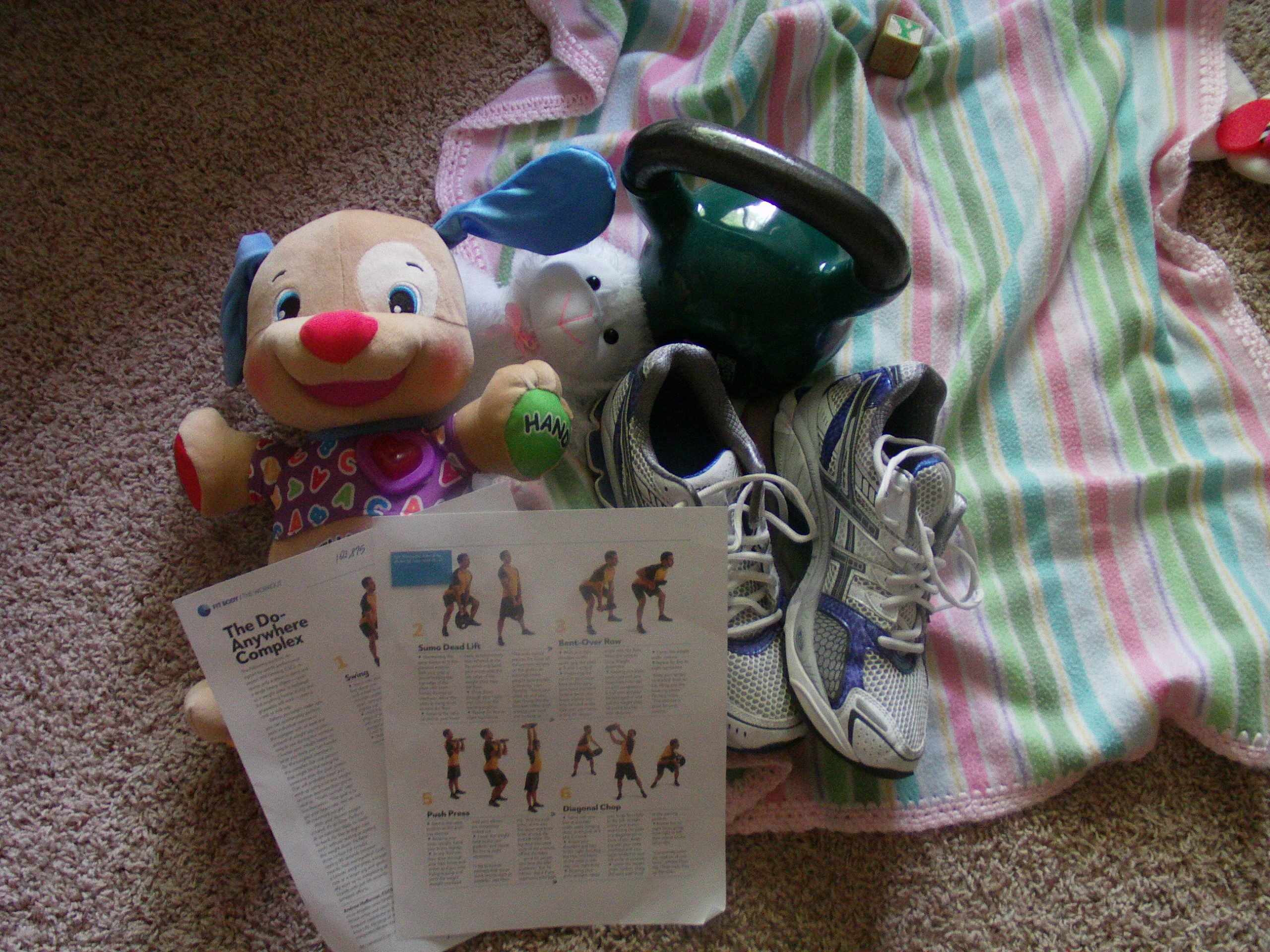 A baby blanket and exercise equipment are pictured on the floor.